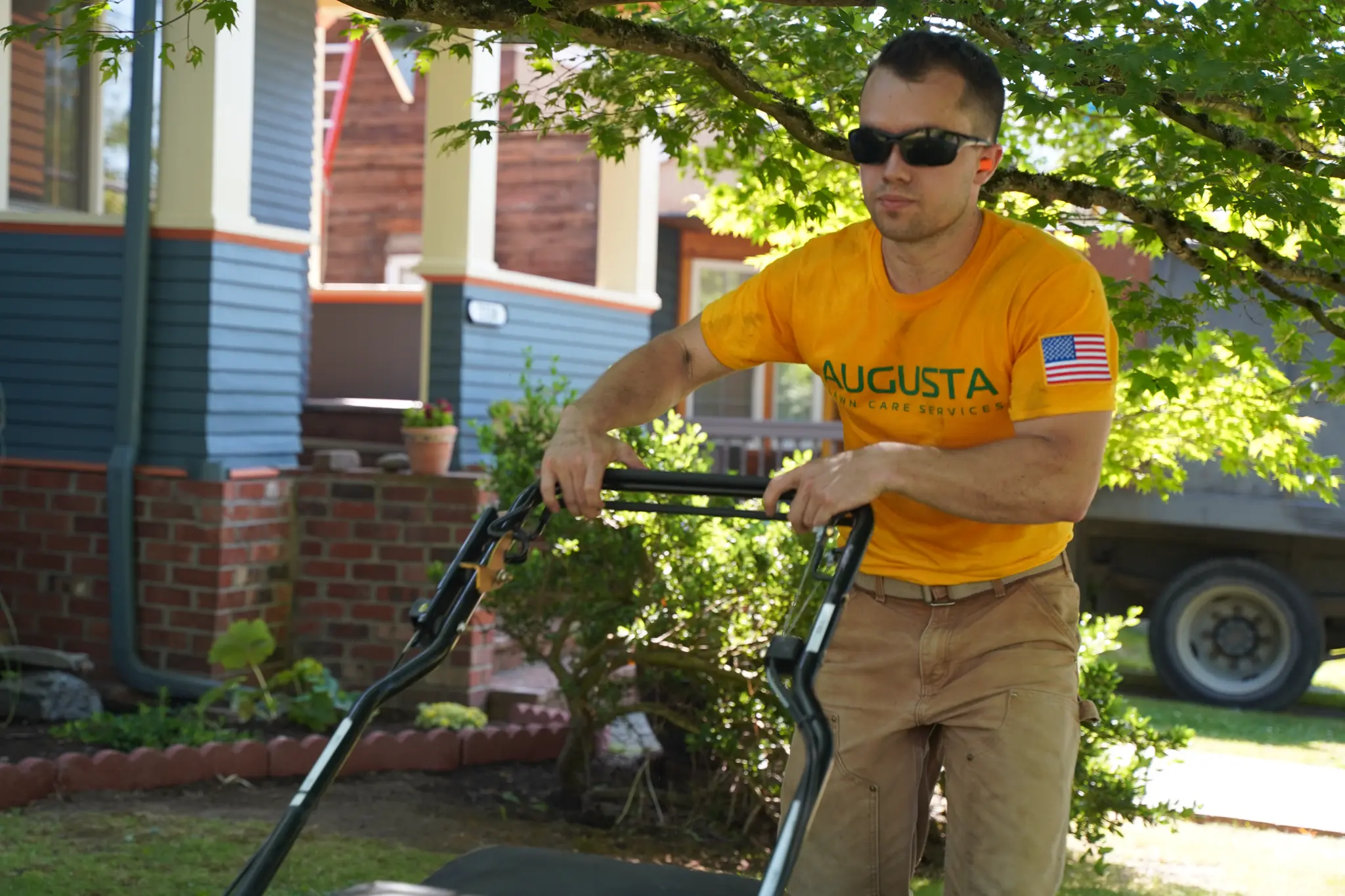 Mike Andes mowing grass in an Augusta Lawn Care shirt